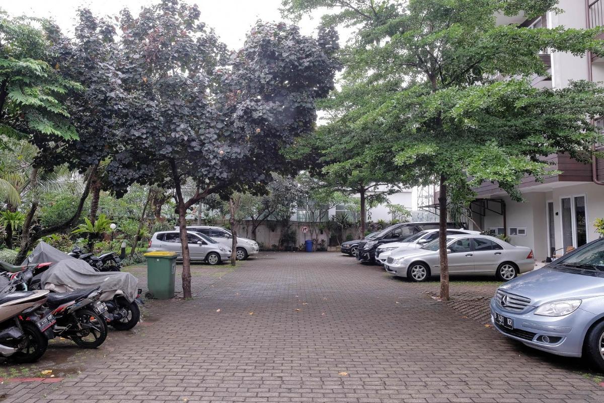 Area parkir mobil dan motor yang luas dan teduh di bawah pepohonan